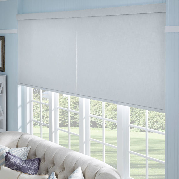 Gray roller shades above a couch window